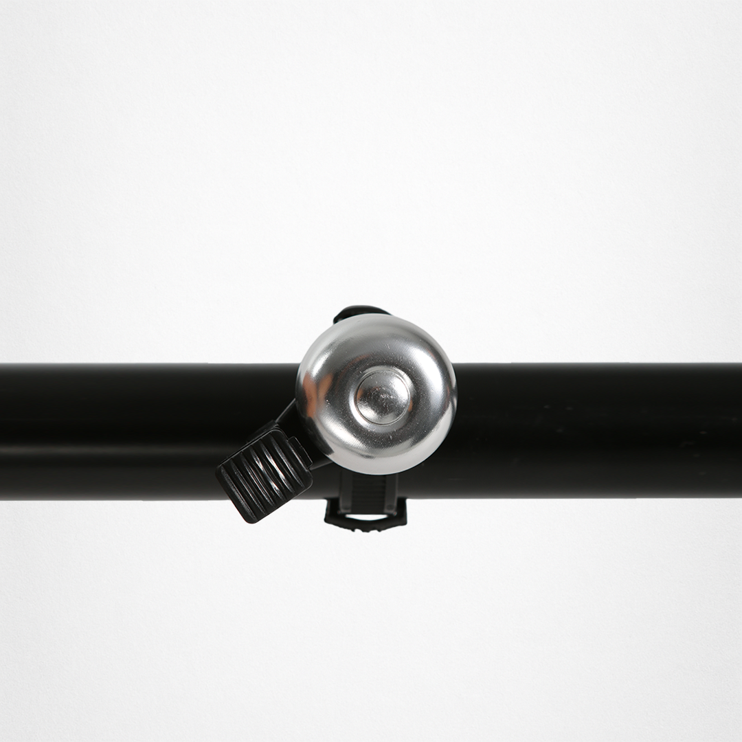 Silberne Fahrradklingel, an einem schwarzen Fahrradlenker befestigt.