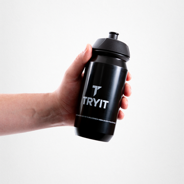 Hand hält eine schwarze Sporttrinkflasche mit weißem "TRYIT"-Logo.