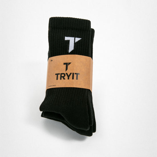 Ein Paar schwarze Sportsocken gepolstert mit weißem "T"-Logo auf dem Socken und brauner Banderole mit einem schwarzem "T"-Logo  und einem „TRYIT“-Schriftzug.