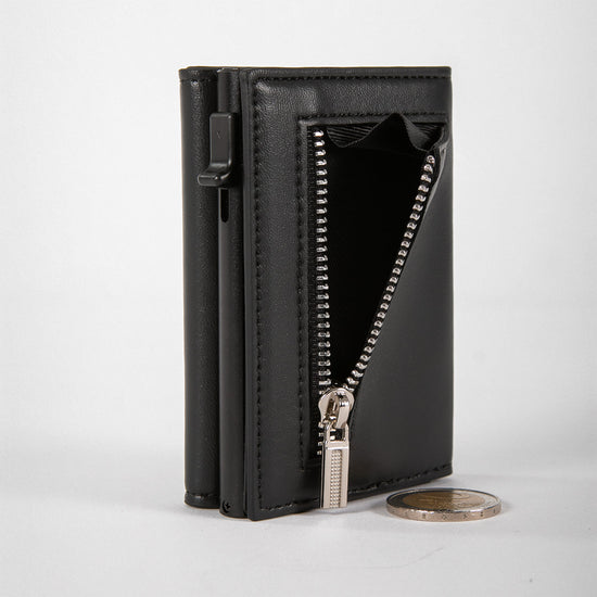 Schwarzes Lederportemonnaie, aufrecht stehend, mit teilweise geöffnetem Reißverschlussfach und einer Zwei-Euro-Münze davor.