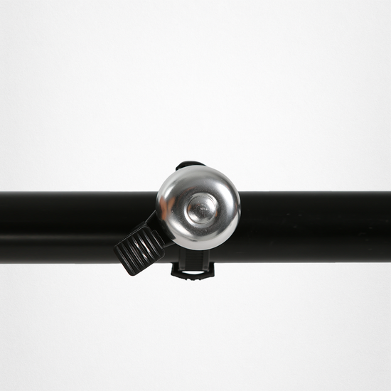 Silberne Fahrradklingel, an einem schwarzen Fahrradlenker befestigt.