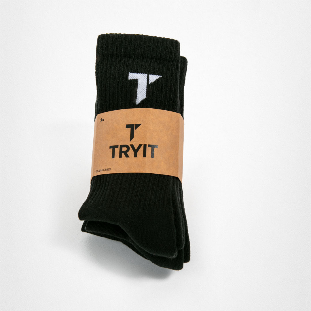 Ein Paar schwarze Sportsocken gepolstert mit weißem "T"-Logo auf dem Socken und brauner Banderole mit einem schwarzem "T"-Logo  und einem „TRYIT“-Schriftzug.