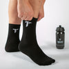Eine Person zieht schwarze Sportsocken mit weißem "T"-Logo an, daneben steht eine schwarze Sport-Trinkflasche mit "TRYIT"-Aufschrift und einem "T"-Logo.